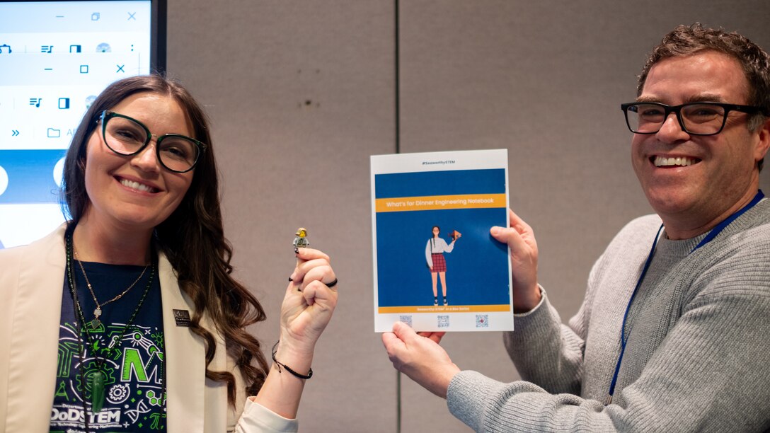 Department of Defense Einstein Fellow Melissa Thompson and former Einstein Fellow Tom Jenkins display a STEM-focused student book activity in West Bethesda, Md., on Feb. 22, 2024.