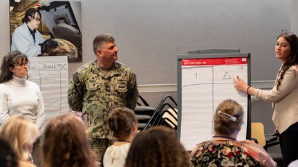 Department of Defense Einstein Fellow Melissa Thompson (right) explains a STEM activity to DOD STEM Ambassadors in West Bethesda, Md., on Feb. 22, 2024.