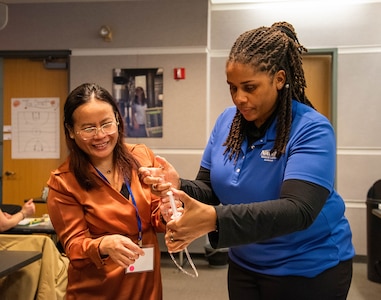 Community Outreach and Student Engagement Coordinator Ashlee Floyd guides a Department of Defense STEM Ambassador through a STEM-In-a-Box activity