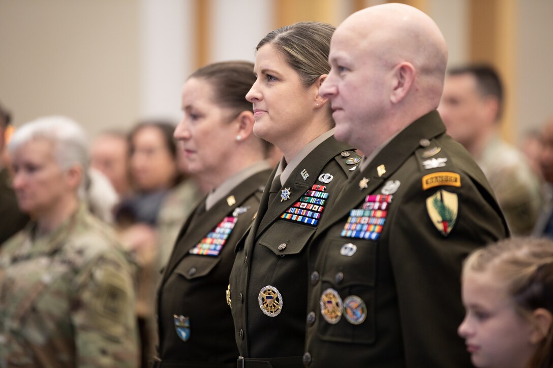 Brig. Gen. Melissa Adamski (center), commander, Military Intelligence Readiness Command, and U.S. Army Col. Michael Adamski stand together at attention.