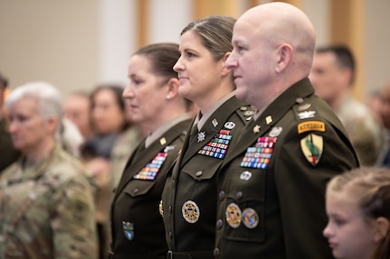 Brig. Gen. Melissa Adamski (center), commander, Military Intelligence Readiness Command, and U.S. Army Col. Michael Adamski stand together at attention.