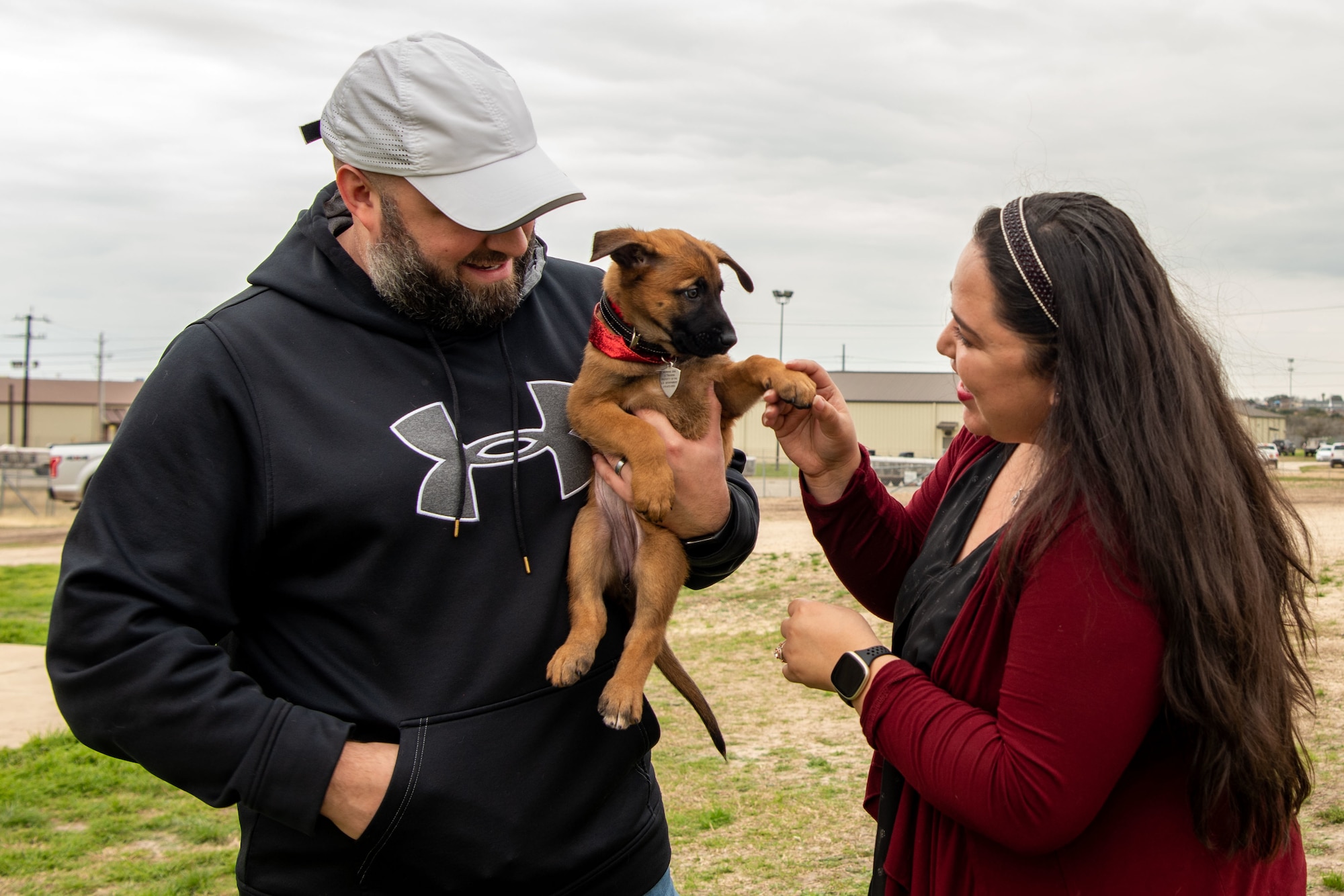 Tammie Lafferty holds the paw of her six-week-old pup, while her husband Matt Lafferty looks on at Joint Base San Antonio-Lackland, Texas, Feb. 14, 2024. This is the second Military Working Dog the couple has fostered with the Department of Defense MWD Puppy Foster Volunteer Program. The couple was inspired to foster a puppy to continue to serve their country after their military retirement. (U.S. Photo by Vanessa R. Adame)