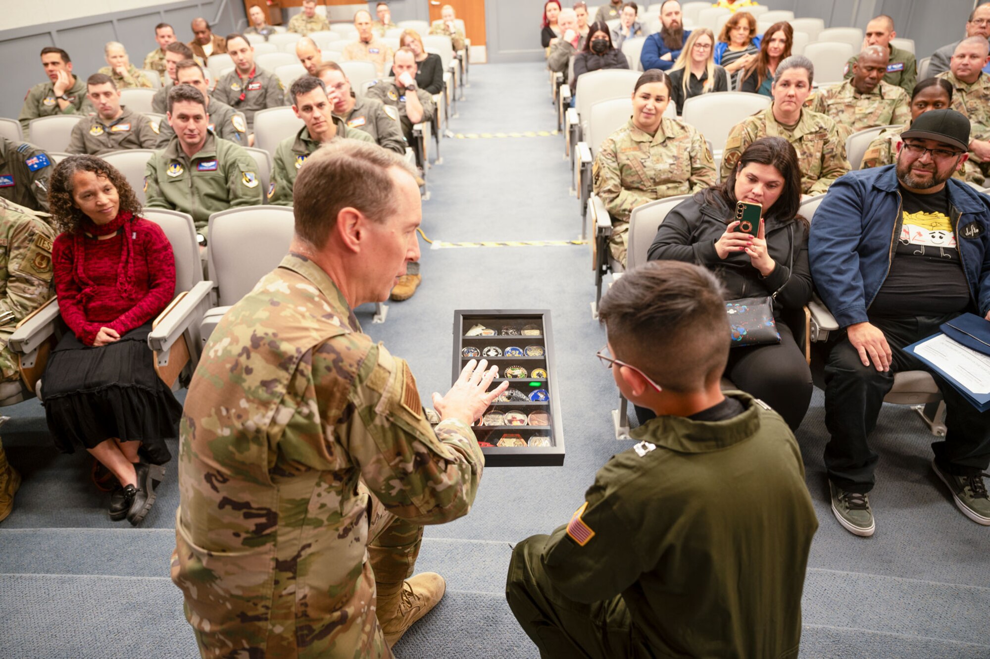 Col. Douglas Wickert, 412th Test Wing commander, presents a collection of coins to nine-year-old Dean Lomelin, Jan. 31, 2024, at Edwards Air Force Base, California.