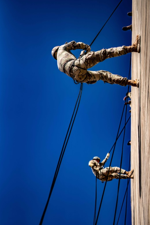 Two soldiers rappel down a tower.