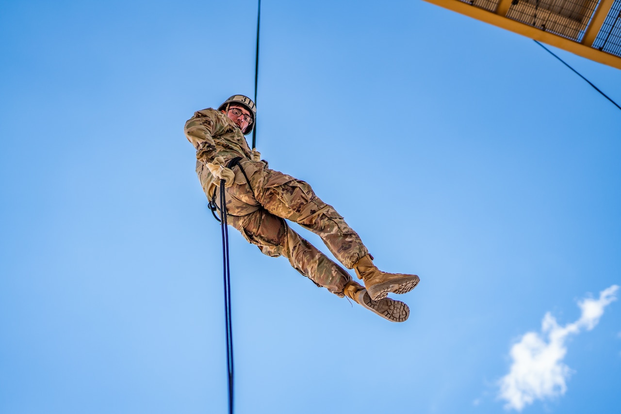 A soldier rappels down a tower.