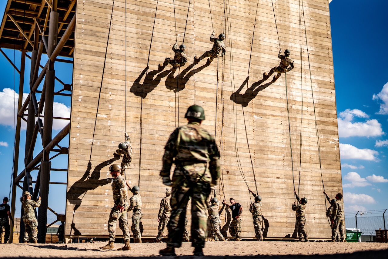 Soldiers rappel down a tower.