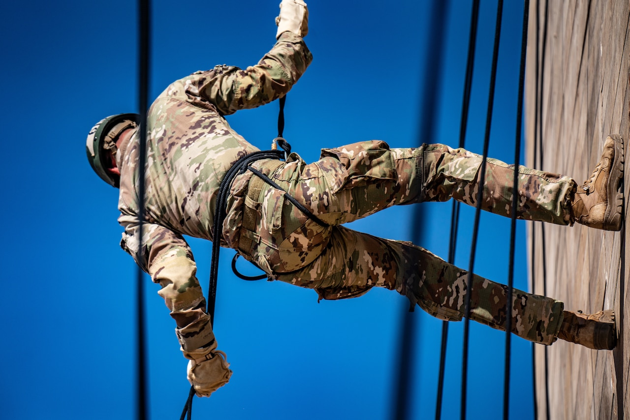 A close-up of a soldier rappelling off a tower.