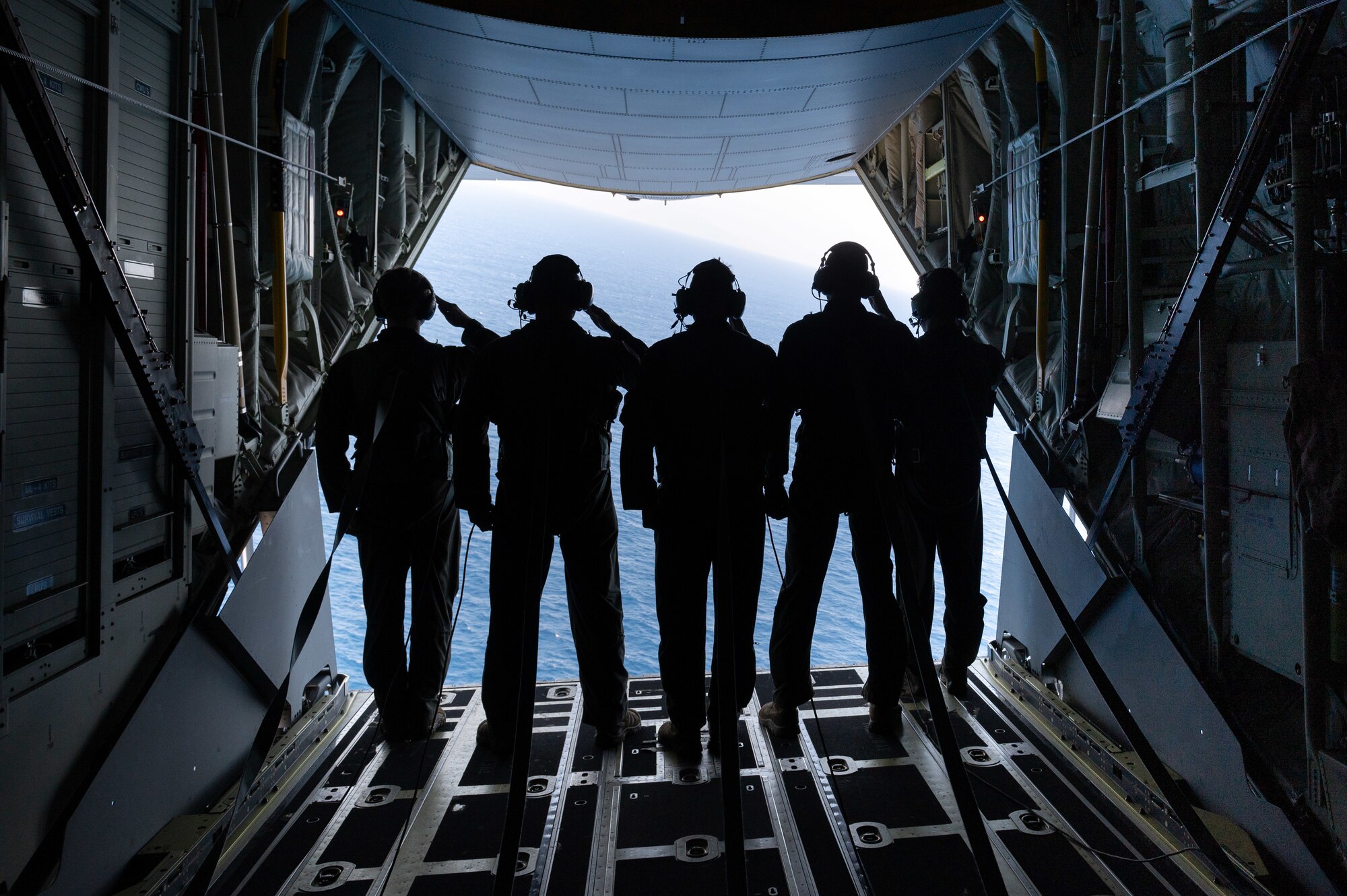 Airmen saluting in the back of an open MC-130J Commando II