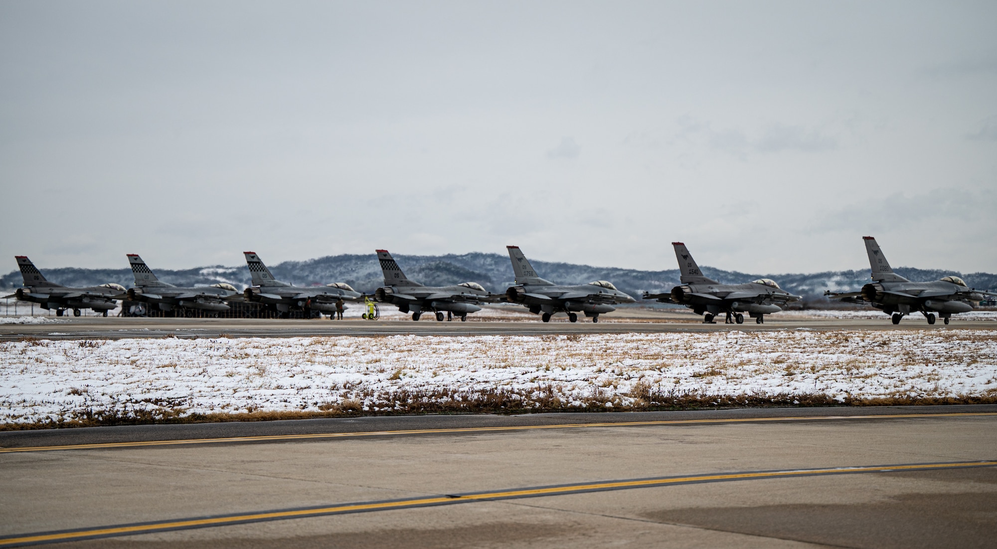 Seven F-16s line up on the runway.