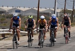 six athletes bike down a road