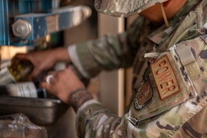 A close-up photo of an Airman's shoulder patch that reads "POWER" while he changes a fuel filter in a generator.