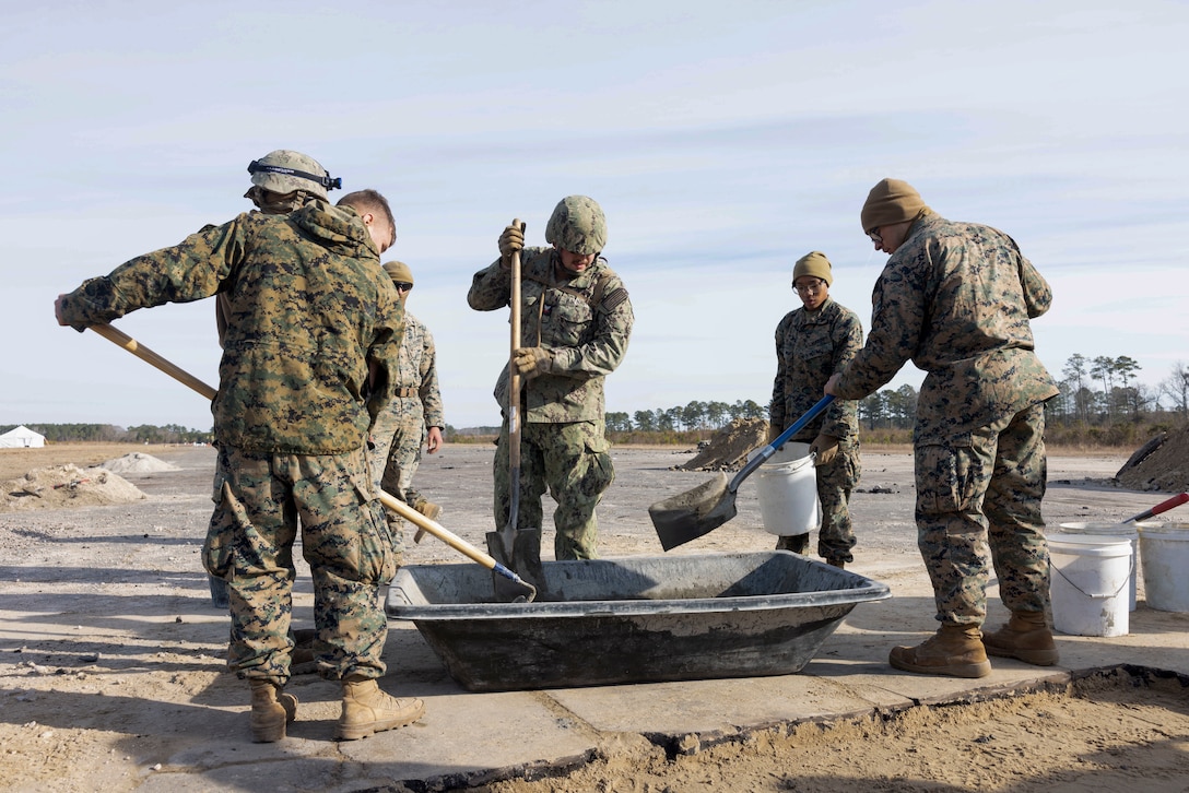 U.S. Marines with 8th Engineer Support Battalion, 2nd Marine Logistics Group and U.S. Navy Sailors with Naval Mobile Construction Battalion 1, mix cement to fill a crater on the airfield’s tarmac during Exercise Winter Pioneer 24, Marine Corps Outlying Field Oak Grove, North Carolina, Feb. 15, 2024. U.S. Marine Corps engineers and U.S. Navy construction force utilized Marine Corps Outlying Field Oak Grove for Marines and Sailors to rehearse establishing and sustaining advanced naval and expeditionary bases that contribute to maritime domain awareness. (U.S. Marine Corps photo by Lance Cpl. Lauralle Walker)