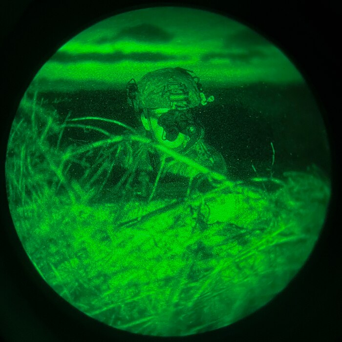 Airman looks from behind cover at night