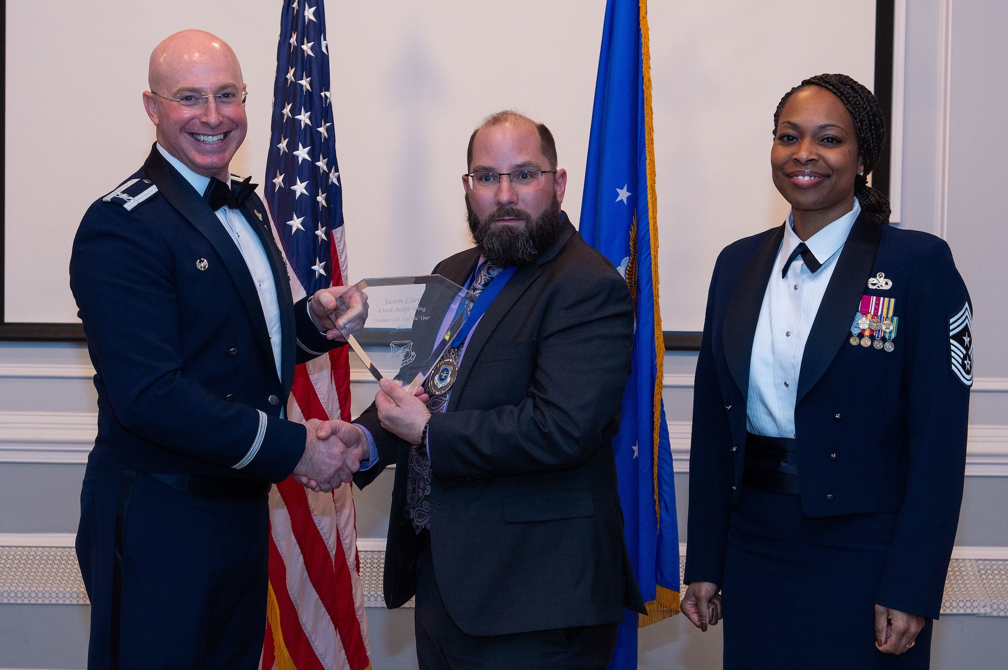 U.S. Air Force Col. Chris McDonald, left, 436th Airlift Wing commander, and U.S. Air Force Chief Master Sgt. Carolyn Russell, right, 436th AW command chief, present Jason Carr, center, 436th Mission Generation Group annual award winner, with a trophy during the 2023 436th AW Annual Awards Ceremony held at the Hartly Volunteer Fire Company in Hartly, Delaware, Feb. 23, 2024. Carr was recognized as the wing’s Civilian-Category I of the Year. (U.S. Air Force photo by Roland Balik)