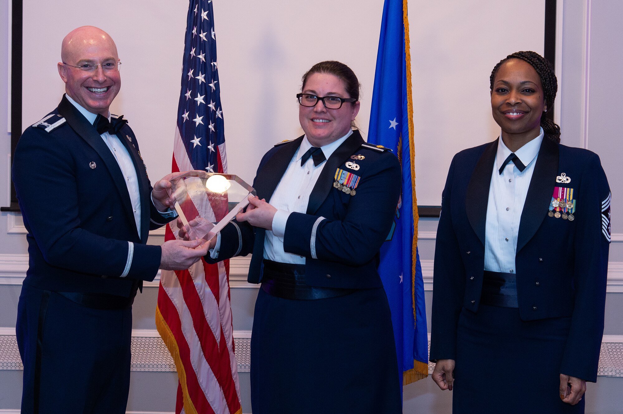 U.S. Air Force Col. Chris McDonald, left, 436th Airlift Wing commander, and U.S. Air Force Chief Master Sgt. Carolyn Russell, right, 436th AW command chief, present U.S. Air Force Maj. Brandi Boos, center, 436th Comptroller Squadron commander, with a trophy during the 2023 436th AW Annual Awards Ceremony held at the Hartly Volunteer Fire Company in Hartly, Delaware, Feb. 23, 2024. Boos accepted the trophy on behalf of Patrick Tulloch, 436th Wing Staff Agency, who was recognized as the wing’s Civilian-Category II of the Year. (U.S. Air Force photo by Roland Balik)
