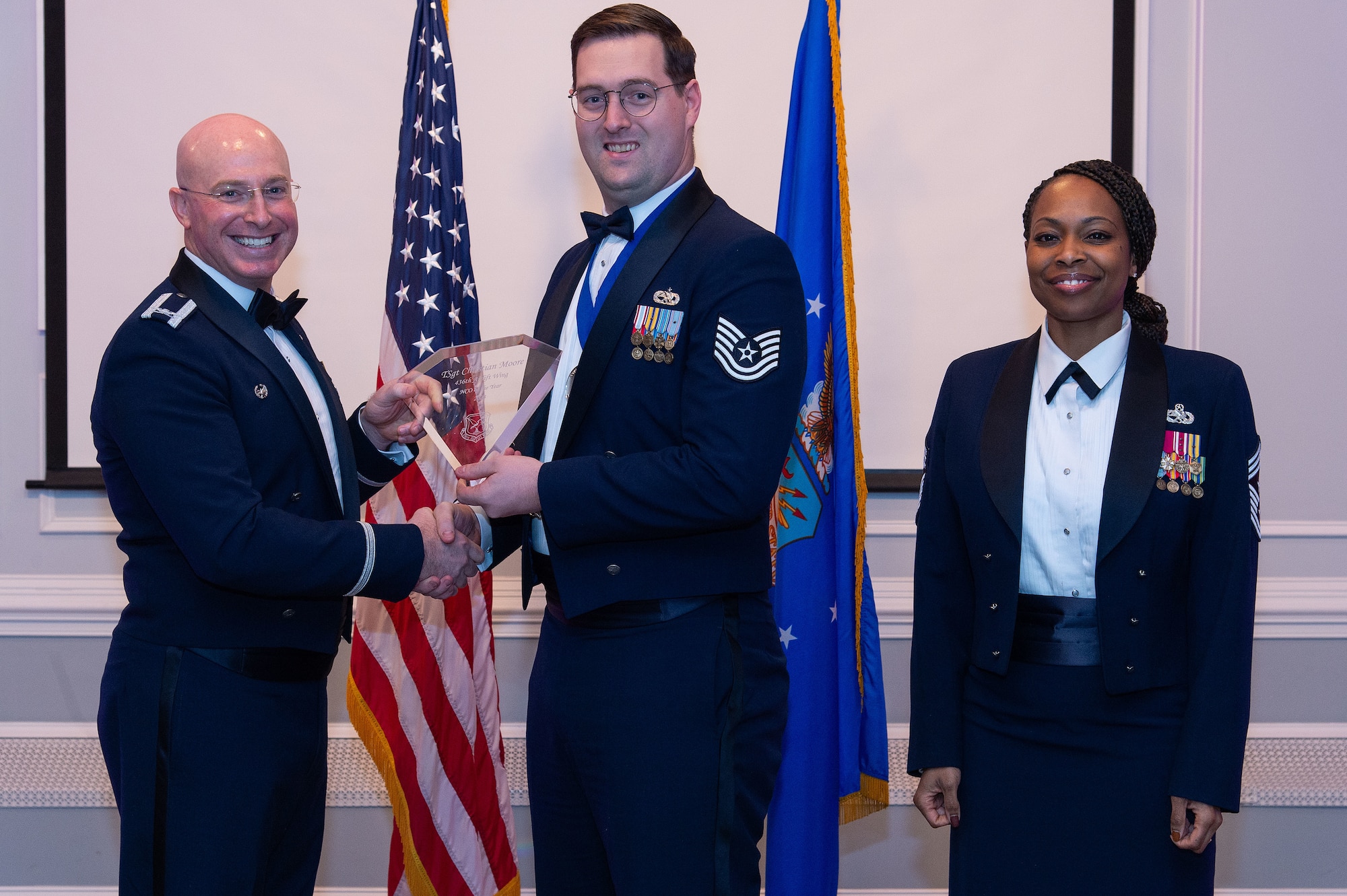 U.S. Air Force Col. Chris McDonald, left, 436th Airlift Wing commander, and U.S. Air Force Chief Master Sgt. Carolyn Russell, right, 436th AW command chief, present U.S. Air Force Tech. Sgt. Christian Moore, center, 436th Mission Generation Group annual award winner, with a trophy during the 2023 436th AW Annual Awards Ceremony held at the Hartly Volunteer Fire Company in Hartly, Delaware, Feb. 23, 2024. Moore was recognized as the wing’s Noncommissioned Officer of the Year. (U.S. Air Force photo by Roland Balik)