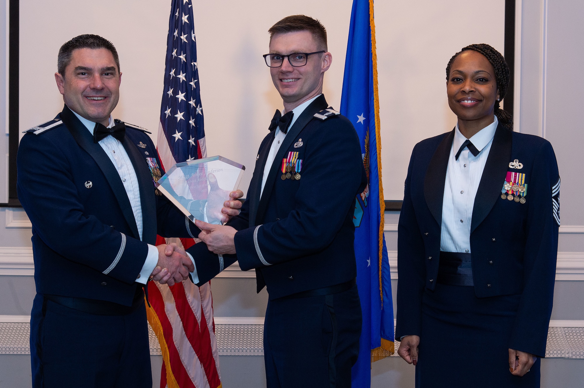 U.S. Air Force Col. Rusty Gohn, left, 436th Airlift Wing deputy commander, and U.S. Air Force Chief Master Sgt. Carolyn Russell, right, 436th AW command chief, present U.S. Air Force Lt. Col. Ian Mazerski, 436th Aircraft Maintenance Squadron commander, center, with a trophy during the 2023 436th AW Annual Awards Ceremony held at the Hartly Volunteer Fire Company in Hartly, Delaware, Feb. 23, 2024. Mazerski accepted the trophy on behalf of U.S. Air Force Master Sgt. Aimee Anderson, 436th Mission Generation Group annual award winner, who was recognized as the wing’s First Sergeant of the Year. (U.S. Air Force photo by Roland Balik)