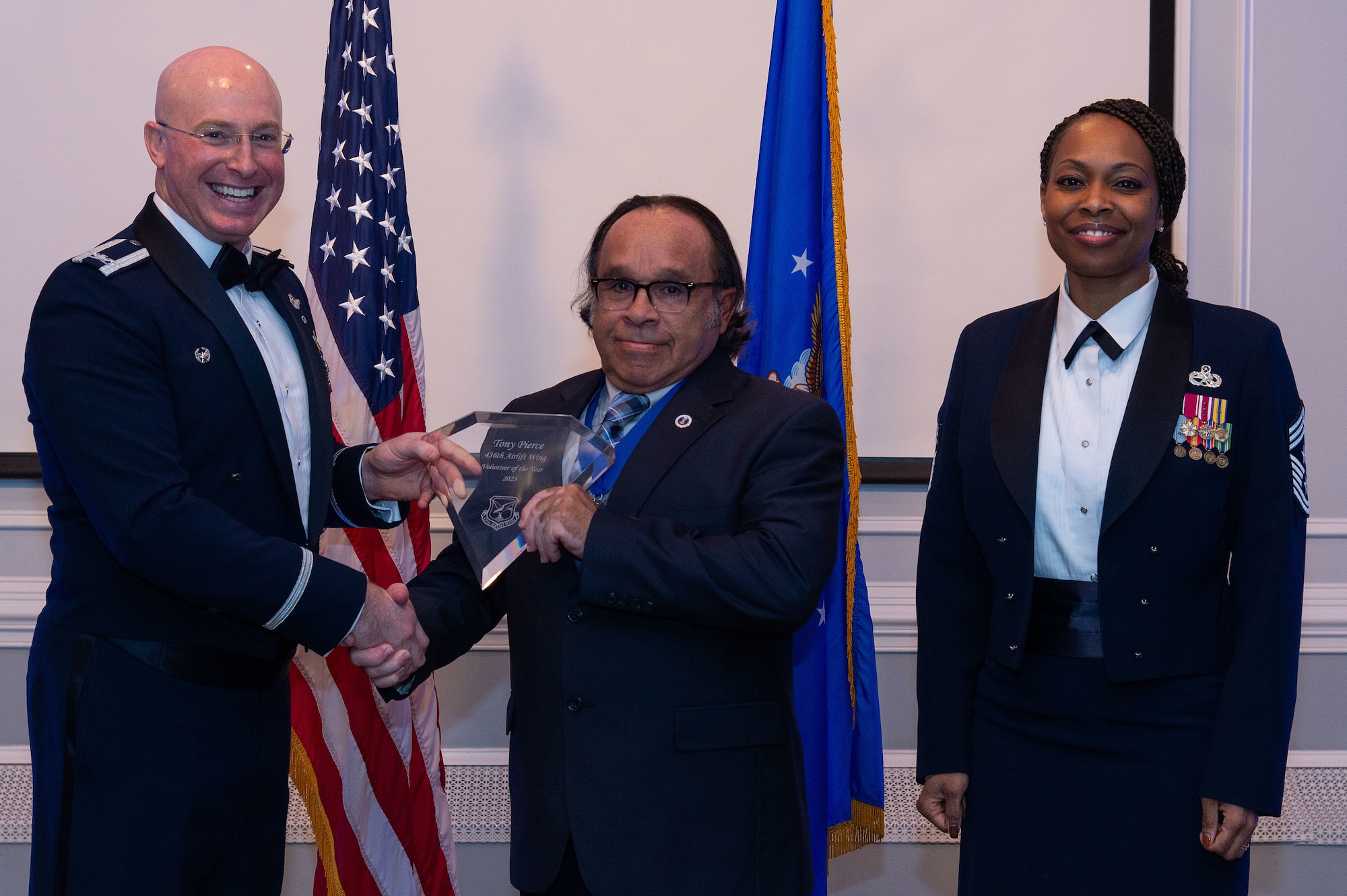 U.S. Air Force Col. Chris McDonald, left, 436th Airlift Wing commander, and U.S. Air Force Chief Master Sgt. Carolyn Russell, right, 436th AW command chief, present Tony Pierce, center, 436th Wing Staff Agency annual award winner, with a trophy during the 2023 436th AW Annual Awards Ceremony held at the Hartly Volunteer Fire Company in Hartly, Delaware, Feb. 23, 2024. Pierce was recognized as the wing’s Civilian Volunteer of the Year. (U.S. Air Force photo by Roland Balik)