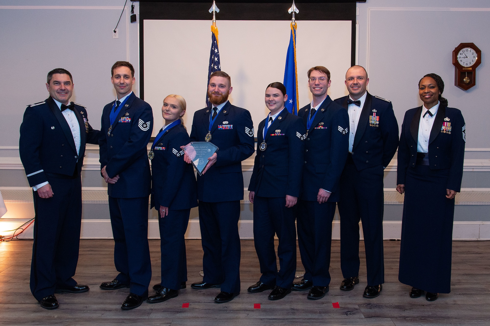 U.S. Air Force Col. Rusty Gohn, left, 436th Airlift Wing deputy commander, and U.S. Air Force Chief Master Sgt. Carolyn Russell, right, 436th AW command chief, present 436th Operations Group members, center, with a trophy during the 2023 436th AW Annual Awards Ceremony held at the Hartly Volunteer Fire Company in Hartly, Delaware, Feb. 23, 2024. The 436th OG Radar, Airfield and Weather Systems flight was recognized as the wing’s Team of the Year. (U.S. Air Force photo by Roland Balik)