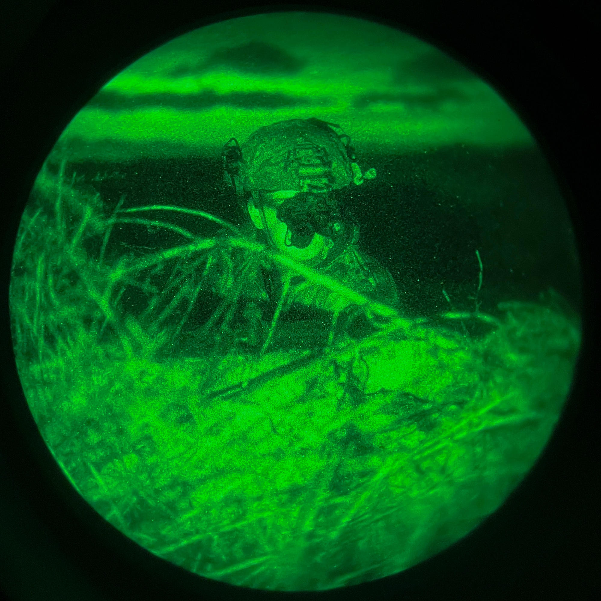 Airman looks from behind cover at night