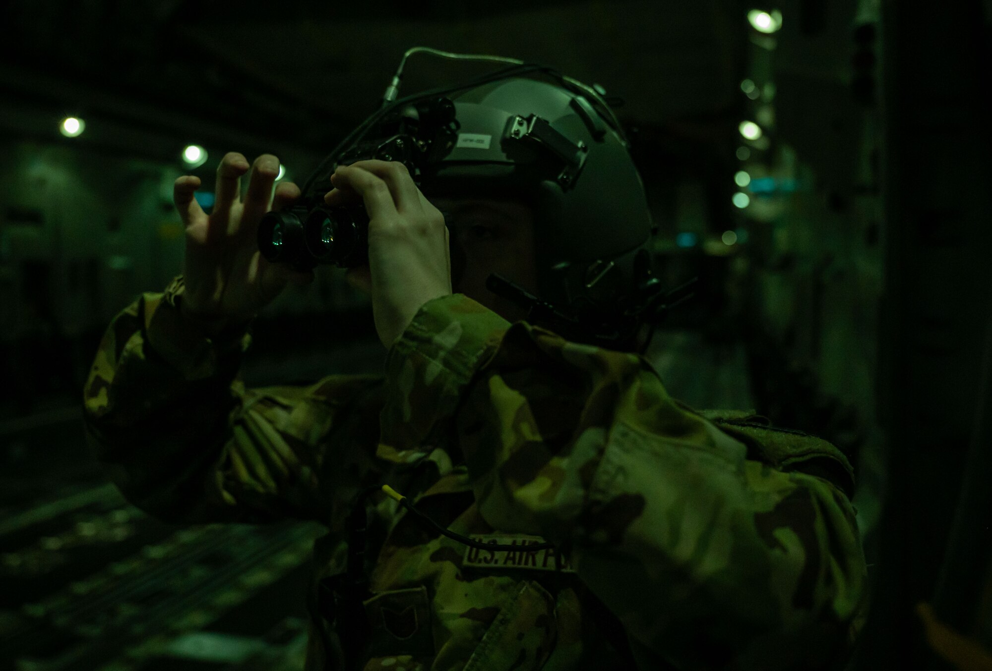 U.S. Air Force Tech. Sgt. Alyssa Kane, 3rd Airlift Squadron loadmaster, adjusts her night vision goggles during a local evening training sortie over Delaware, Feb. 26, 2024. The 3rd AS conducted local training in preparation to support worldwide airlift capabilities to include clandestine delivery, extraction and airdrop of special operations forces and equipment. (U.S. Air Force photo by Airman 1st Class Amanda Jett)