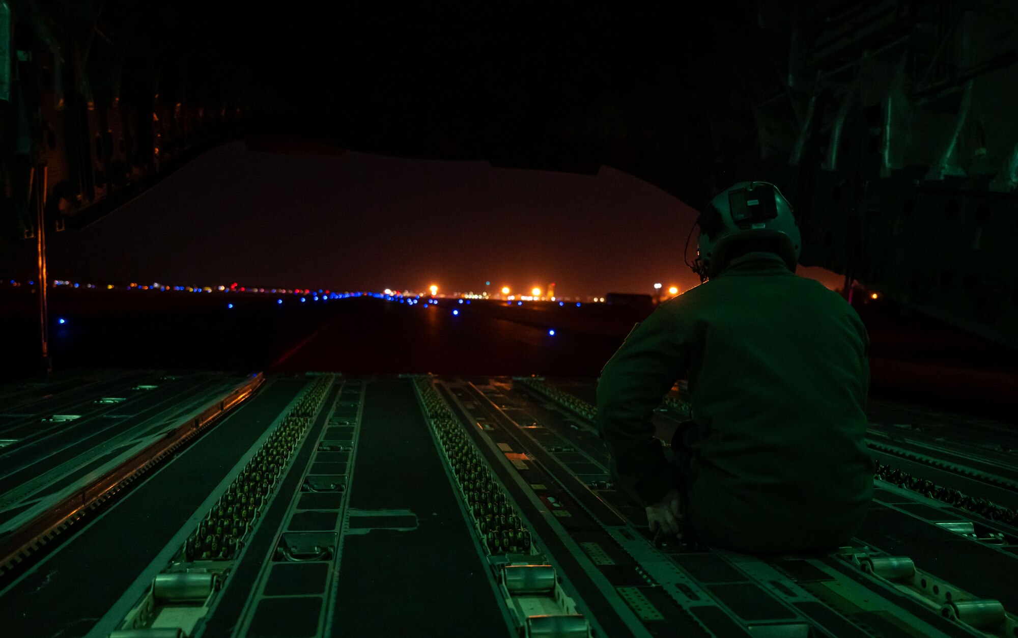 U.S. Air Force Senior Airman Charles Arnold, 3rd Airlift Squadron loadmaster, sits on the aft ramp of a taxiing C-17 Globemaster III during a local evening training sortie at Dover Air Force Base, Delaware, Feb. 26, 2024. The 3rd AS conducted local training in preparation to support worldwide airlift capabilities to include clandestine delivery, extraction and airdrop of special operations forces and equipment. (U.S. Air Force photo by Airman 1st Class Amanda Jett)