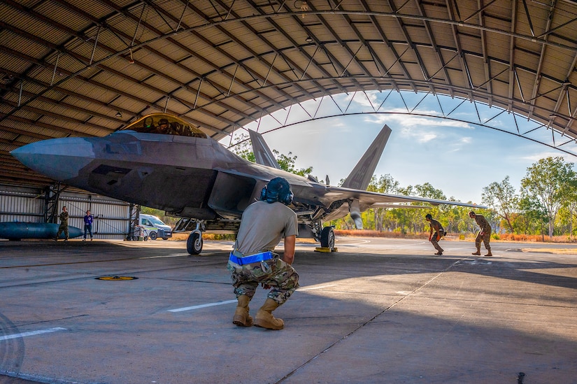 Service members in uniform inspect a jet.