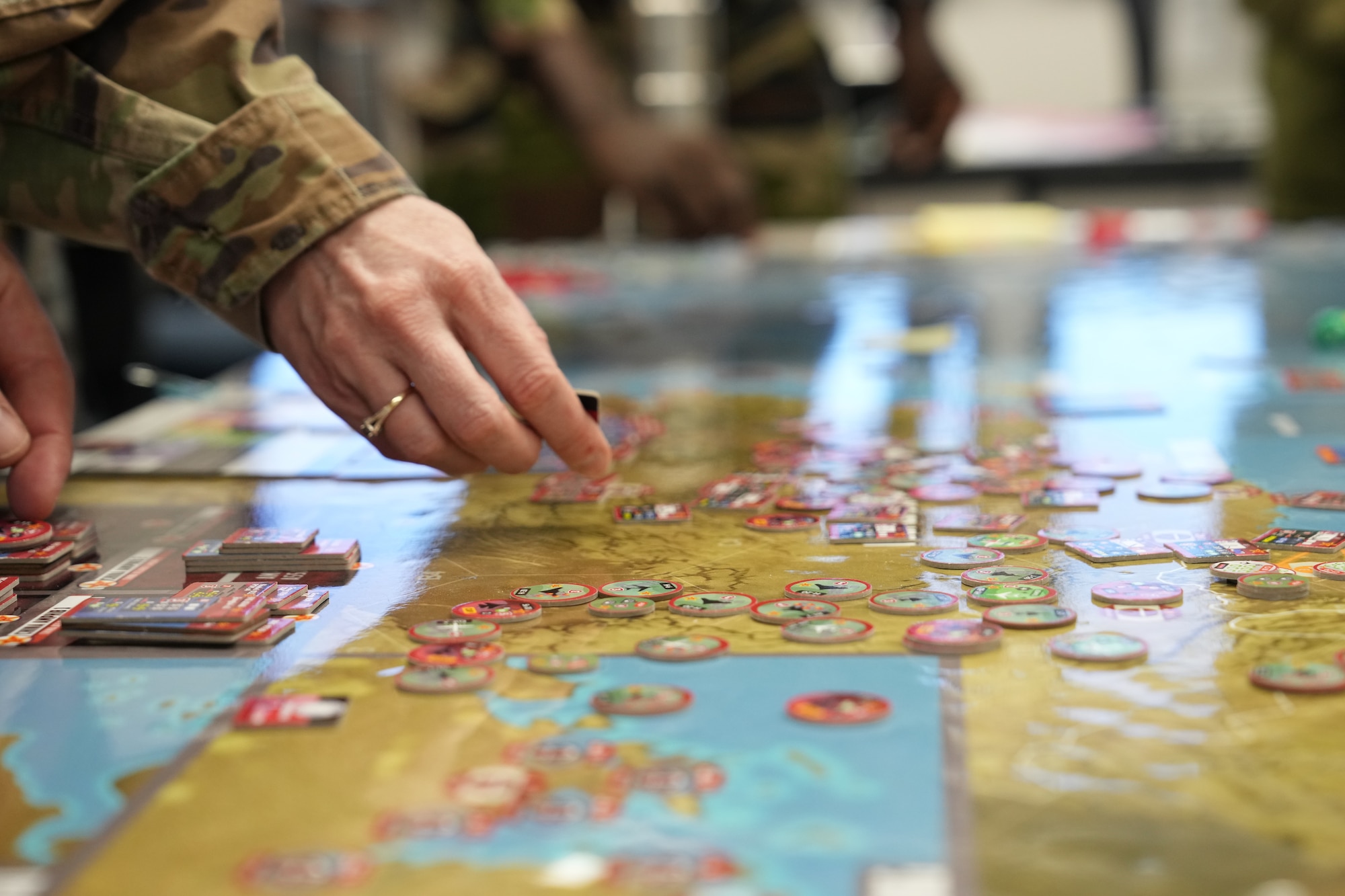 Students move pieces around the board during a war-game based on Pacific conflict while attending Air War College at Maxwell Air Force Base, Alabama, December 21, 2023. Game phases are actioned with a deck of cards, spawning new and viable assets with each play. These items can range from instituting an element of air superiority to launching an information campaign.