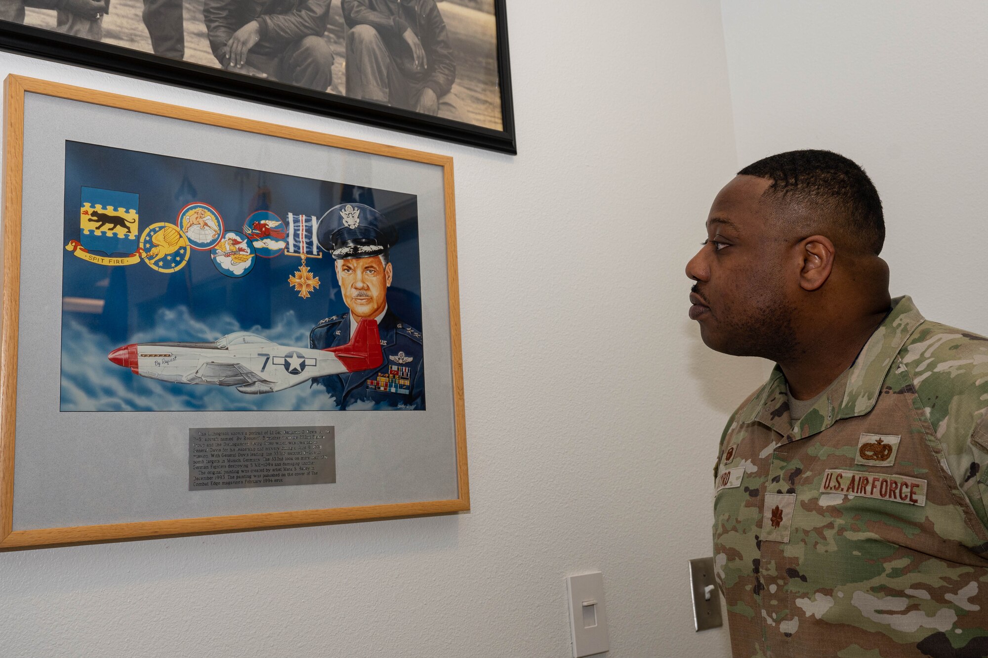 U.S. Air Force Maj. Gabriel Byrd, 525 Fighter Generation Squadron commander at Joint Base Elmendorf-Richardson poses with memorabilia of the Tuskegee Airmen showcased at the 477 Fighter Group building.