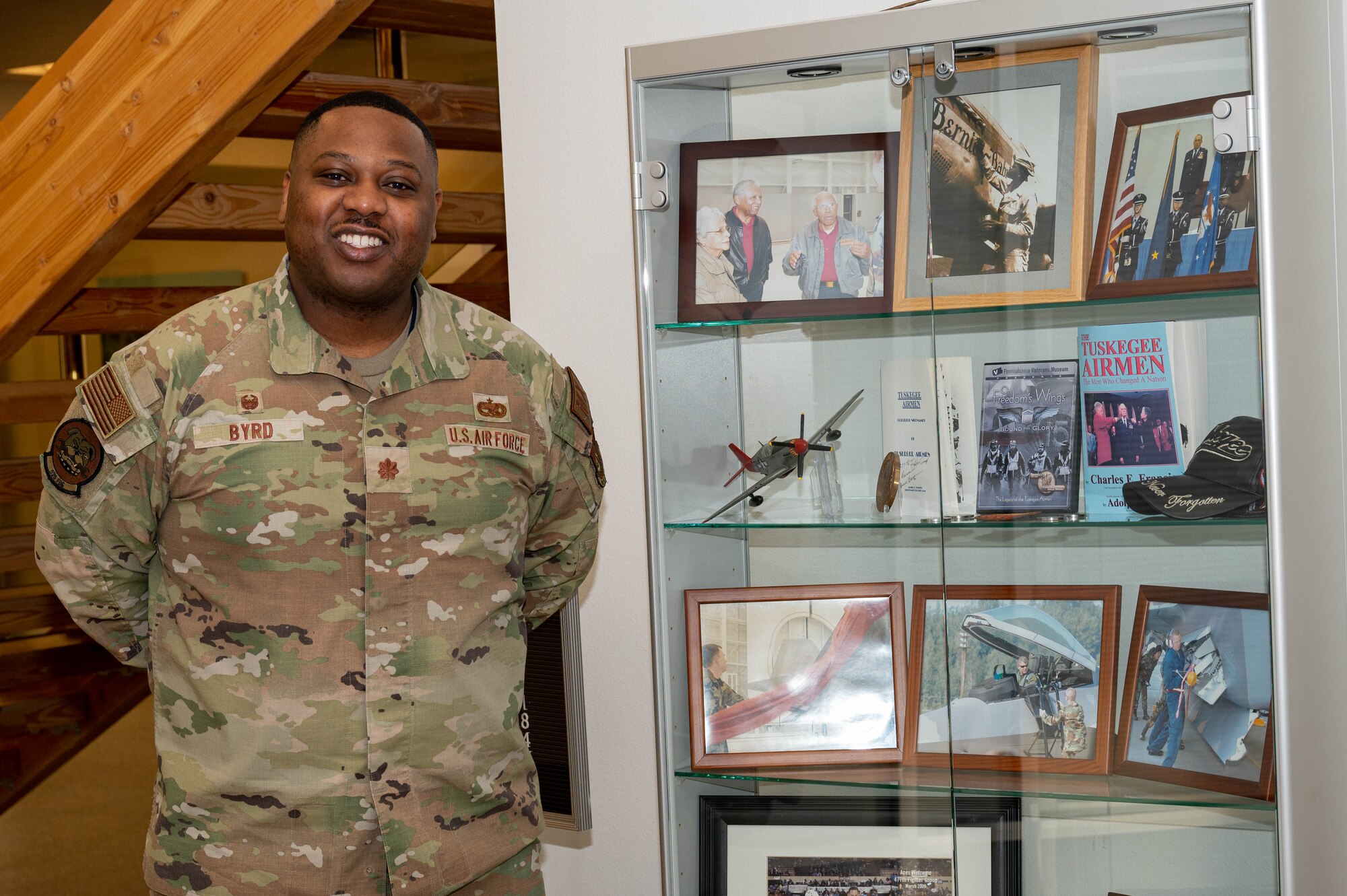 U.S. Air Force Maj. Gabriel Byrd, 525 Fighter Generation Squadron commander at Joint Base Elmendorf-Richardson poses with memorabilia of the Tuskegee Airmen showcased at the 477 Fighter Group building.