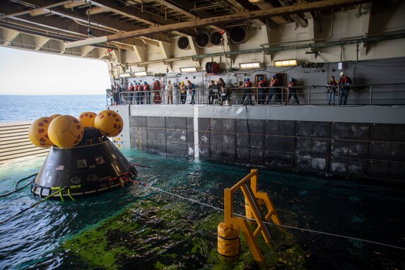 U.S. Navy Sailors stabilize NASA’s crew module test article (CMTA) during rehearsal for launching from the well deck aboard San Antonio-class amphibious transport dock ship USS San Diego (LPD 22) during Underway Recovery Test 11, Feb. 22, 2024. In preparation for NASA’s Artemis II crewed mission, which will send four astronauts in Orion beyond the Moon, NASA and the Department of Defense will conduct a series of tests to demonstrate and evaluate the processes, procedures, and hardware used in recovery operations for crewed lunar missions. The U.S. Navy has many unique capabilities that make it an ideal partner to support NASA, including its amphibious ships with the ability to embark helicopters, launch and recover small boats, three-dimensional air search radar and advanced medical facilities. (U.S. Navy photo by Mass Communication Specialist 1st Class Brandon Woods)