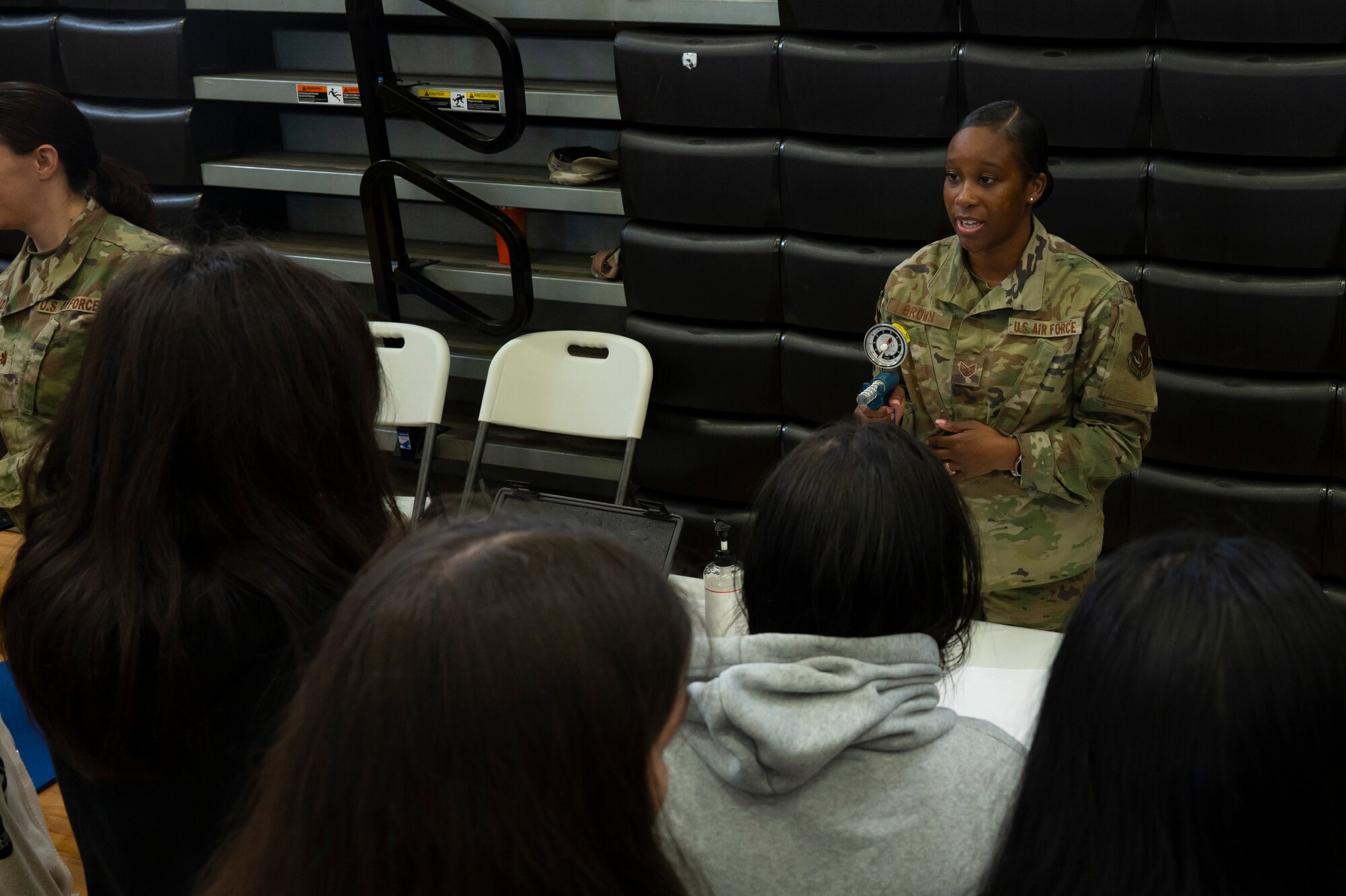 U.S. Air Force Staff Sgt. Ashley Brown, 36th Operational Medical Readiness Squadron physical therapy technician, speaks to students about physical therapy during the Tiyan High School Health Fair in Barrigada, Guam, Feb. 23, 2024. At the fair Airmen from the 36th Civil Engineer Squadron and 36th Medical Group demonstrated carrying a patient, applying a tourniquet, and walked students through various physical therapy exercises. (U.S. Air Force photo by Airman 1st Class Spencer Perkins)