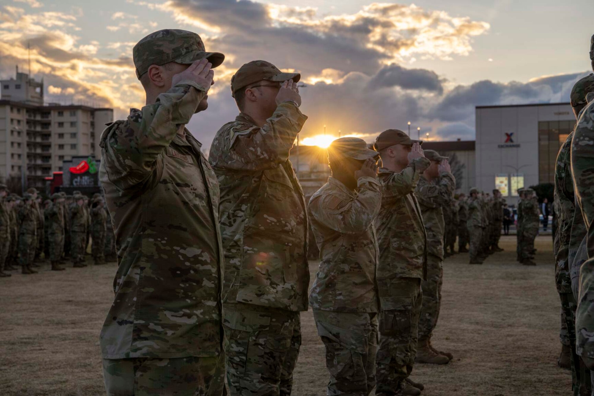 Military members salute during a retreat ceremony at Yokota Air Base, Japan, Feb. 15, 2024. To honor the GUNDAM 22 aircrew, Yokota community members joined to hold a memorial service and formation. (U.S. Air Force photo by Airman 1st Class Samantha White)