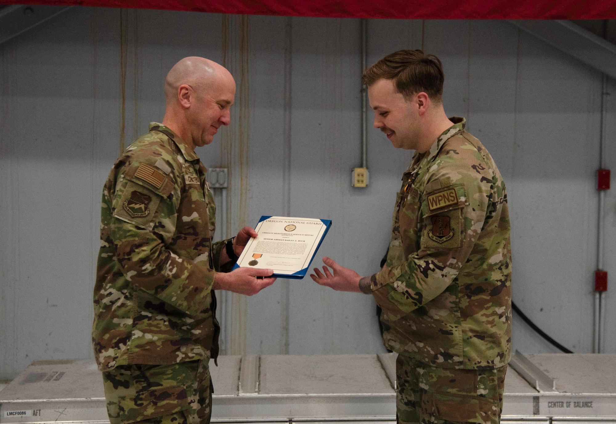 Col. David Christensen, 142nd Maintenance Group commander, presents 142nd Aircraft Maintenance Squadron Senior Airman Bailey Buck with a meritorious service medal for acts of bravery Feb. 25, 2024, at Portland Air National Guard Base, Ore. Fenwick and a fellow Airman intervened when a truck went off the road in Eastern Oregon in May 2023.
