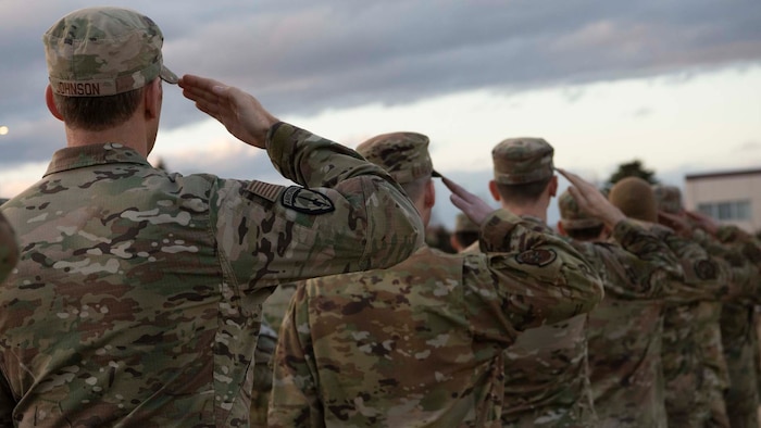Military members salute during a retreat ceremony at Yokota Air Base, Japan, Feb. 15, 2024. Communities unite to commemorate the crew and show solidarity with those grieving, fostering strength and support after the aircraft mishap on Nov. 29, 2023. (U.S. Air Force photo by Airman 1st Class Samantha White)