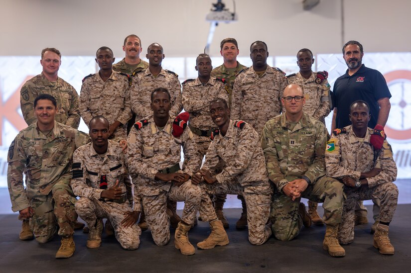 Soldiers pose with Djibouti counterparts in a large room.