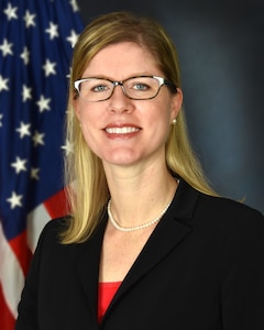 A portrait of Daniele Kurze seated in front of an Americal flag