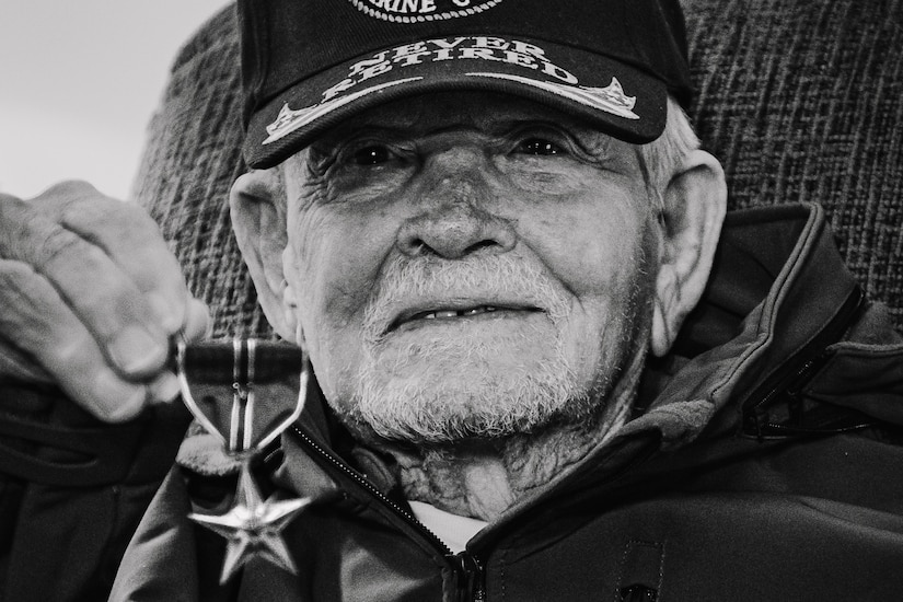 A black and white photo of veteran holding a medal in his hand.