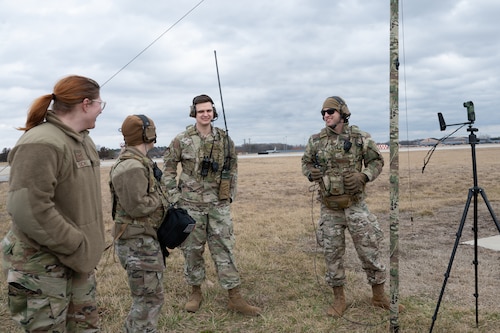 Msgt. Rodney stands with three other Airmen next to weather-sensing equipment on the Scott Airfield.