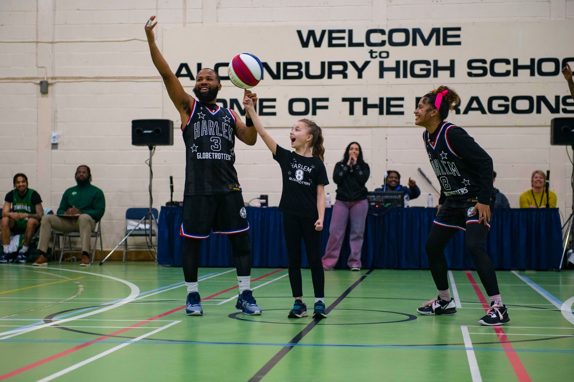 Darnell “Speedy” Artis, Harlem Globetrotters guard, left, helps a member of the crowd spin a basketball on her finger at RAF Alconbury