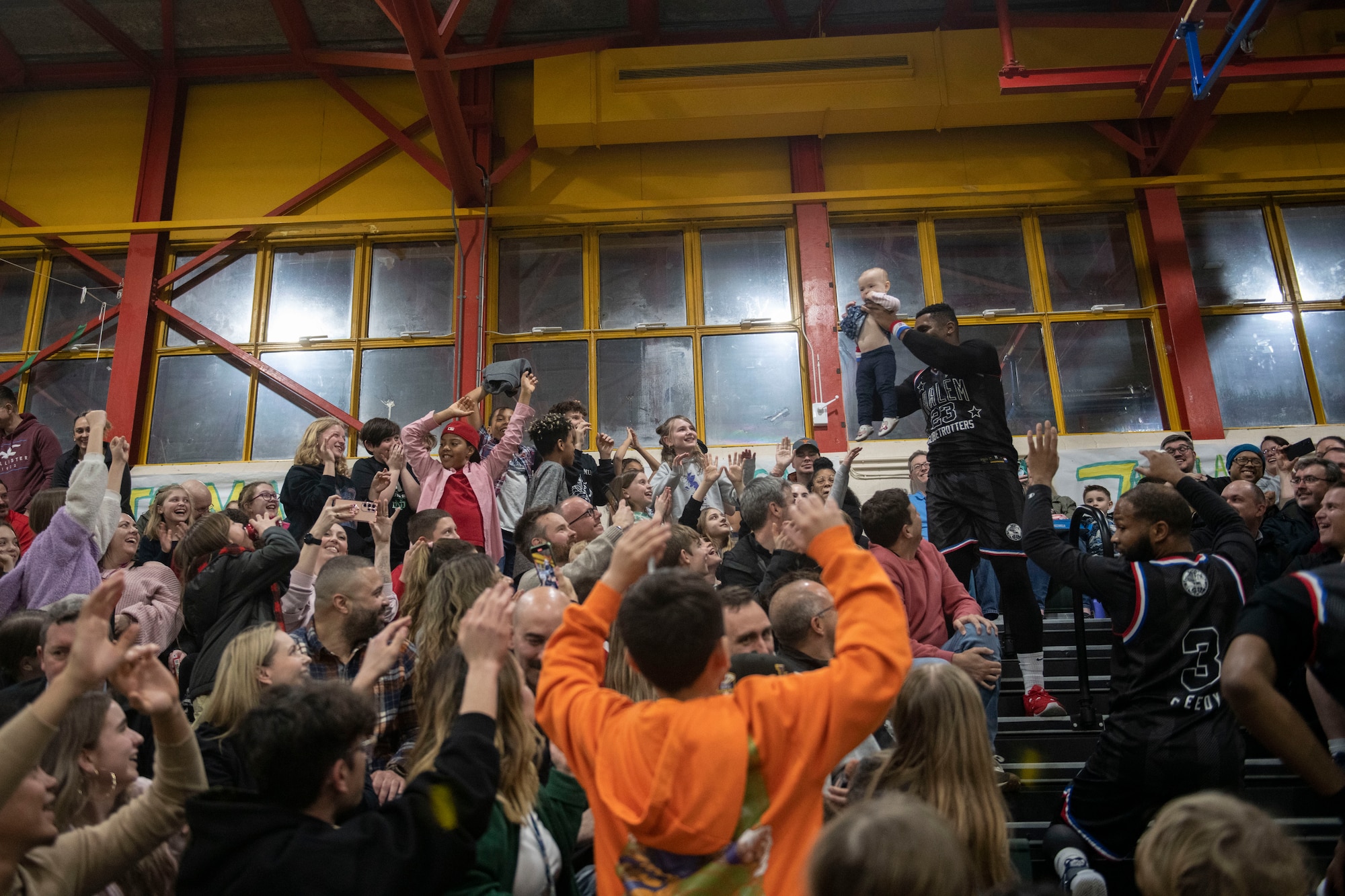 Corey “Thunder” Law, Harlem Globetrotters showman, raises a baby in the crowd at RAF Alconbury