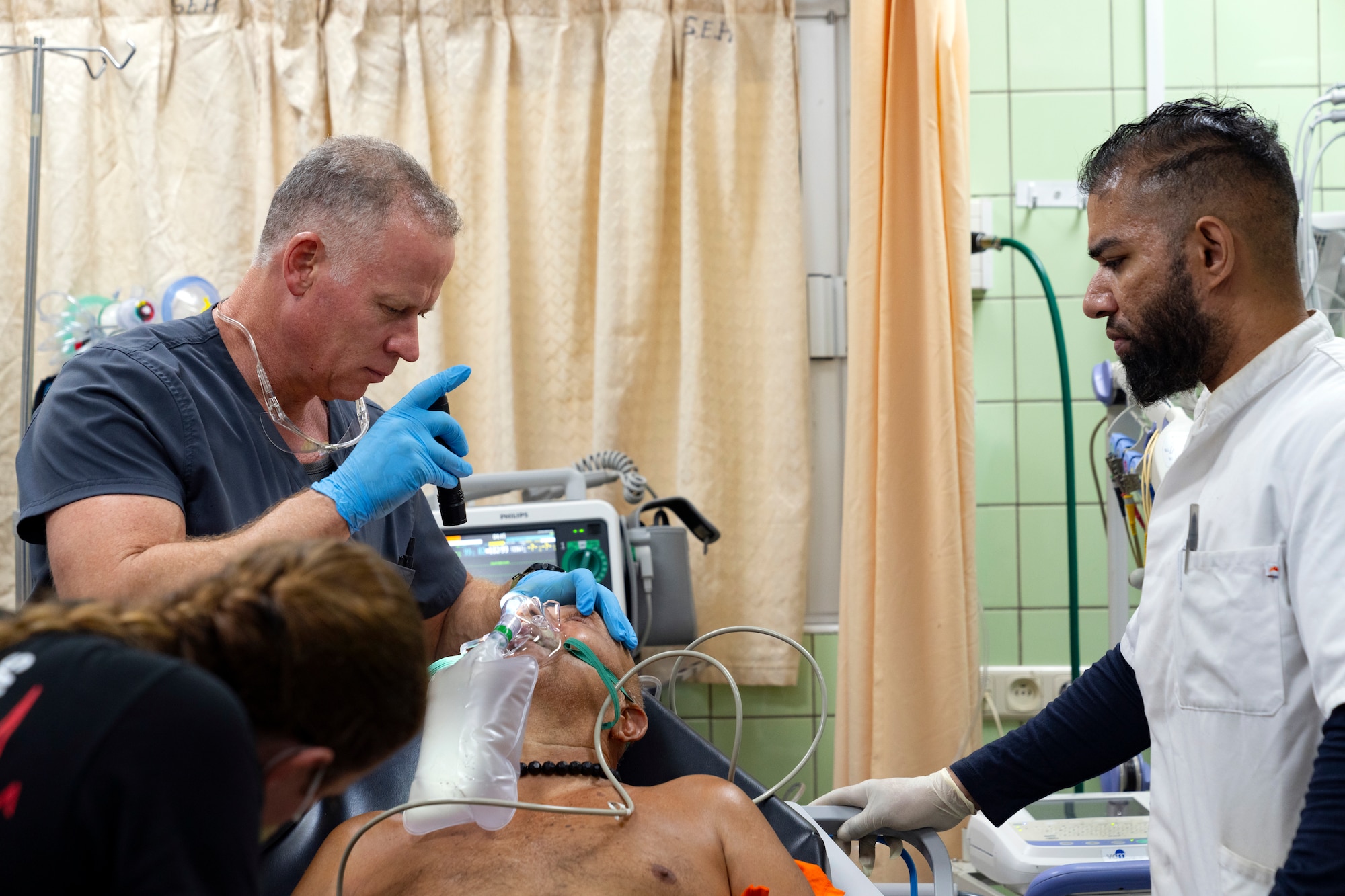 U.S. Air Force reservist Lt. Col. Jesse Wells, left, emergency room physician assigned to the 349th Medical Squadron, uses a flashlight to examine a patient's eyes at Paramaribo’s Academic Hospital in Suriname, Feb. 20, 2024.