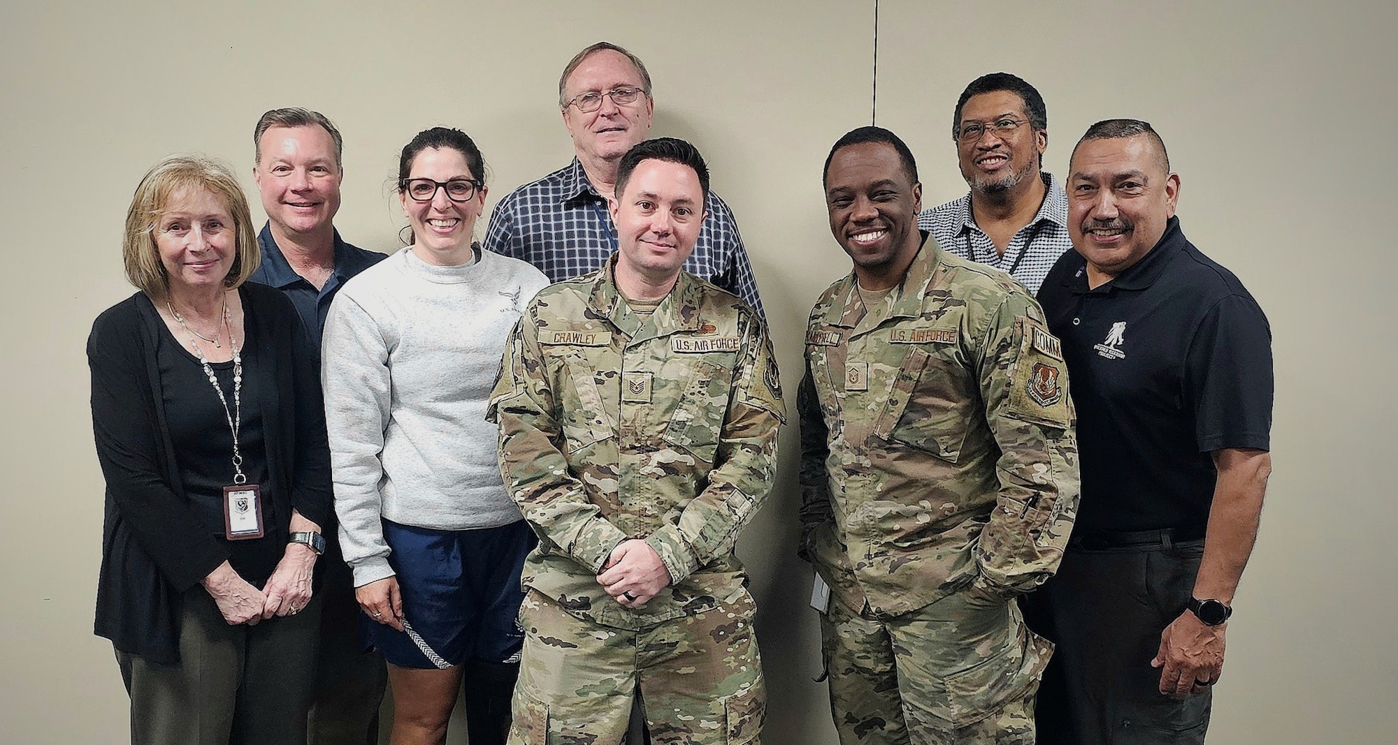 Eight members of the team stand together, smiling at the camera.