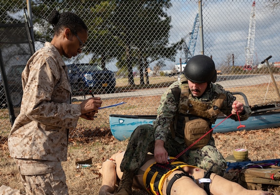 240126-N-KC192-1243 PORTSMOUTH, Va. (Jan. 26, 2024) Hospital Corpsman 2nd Class William Wiegmann, a general duty corpsman assigned to Navy Region Readiness and Mobilization Command (REDCOM) Norfolk, applies a pelvic binder to a simulated patient while Chief Hospital Corpsman Tianna Blackmon, an active duty for operational support reservist and Naval Medical Forces Atlantic (NMFL) regional reserve program director, evaluates his knowledge during a Tactical Combat Casualty Care (TCCC) Tier 3 "Train the Trainer" and pilot course on board Naval Support Activity (NSA) Hampton Roads - Portsmouth Annex, Jan. 26, 2024. The two-week course certified 15 TCCC providers that were also able to provide in-depth feedback on course improvements. TCCC Tier 3 is a combat medic course that provides in-depth life saving techniques, technical information and strategies for Department of Defense first responders, and ensures students receive the necessary hands-on training experience that is required for U.S. Navy medical forces to maintain deployment readiness. (U.S. Navy photo by Mass Communication Specialist 2nd Class Levi Decker)