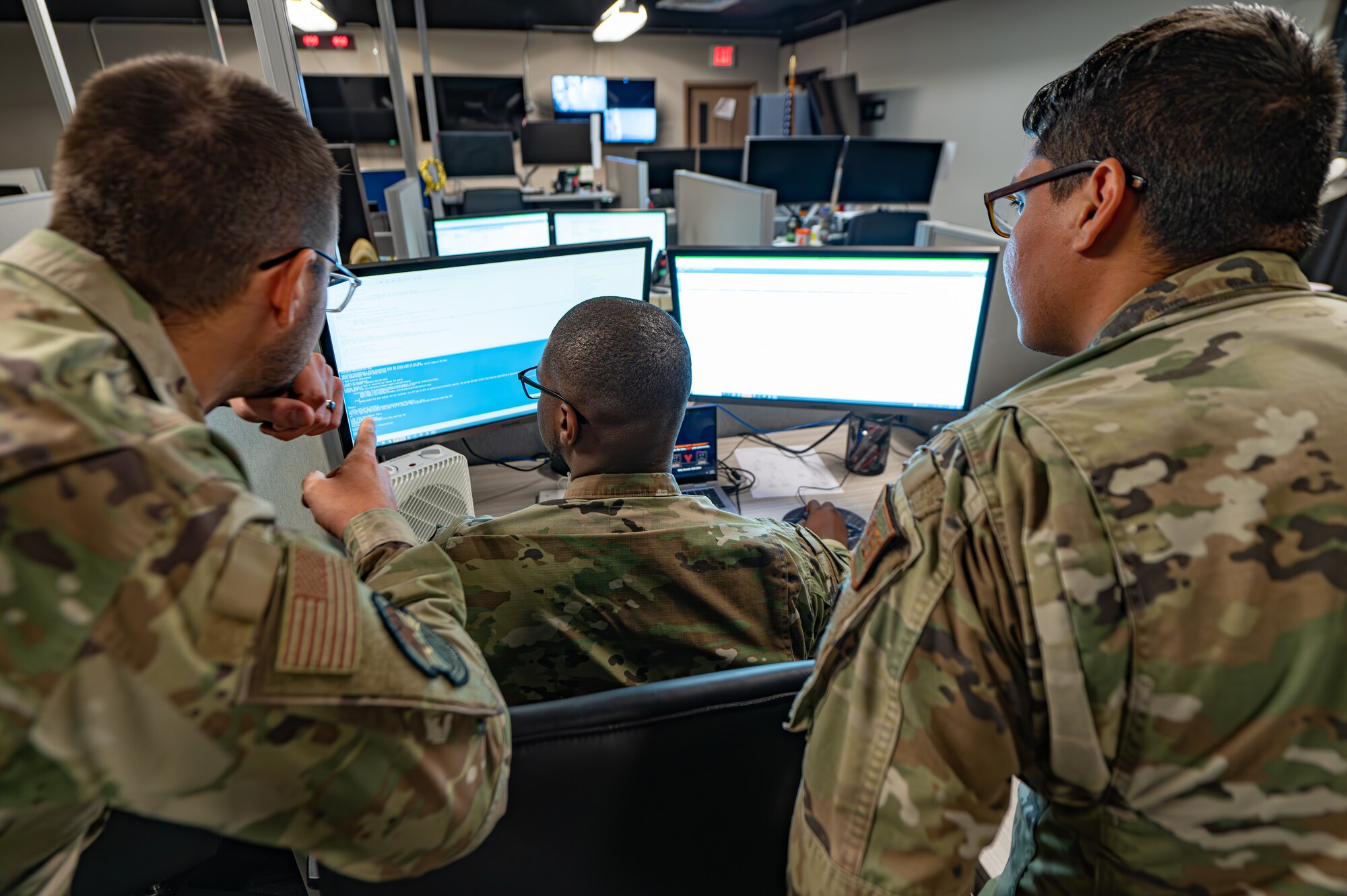 U.S. Air Force Senior Airman Malkiel Shimonar, left, Senior Airman Jared Gilbert, middle, and Airman 1st Class Duarte Lopez, right, 6th Communications Squadron cyber operations specialists, collaborate on a program error at MacDill Air Force Base, Florida, Feb. 28, 2024.