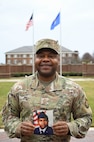 Chief Lawton holds a photo of himself as a young Airman straight out of boot camp while on the ceremonial lawn on Joint Base Anacostia-Bolling.