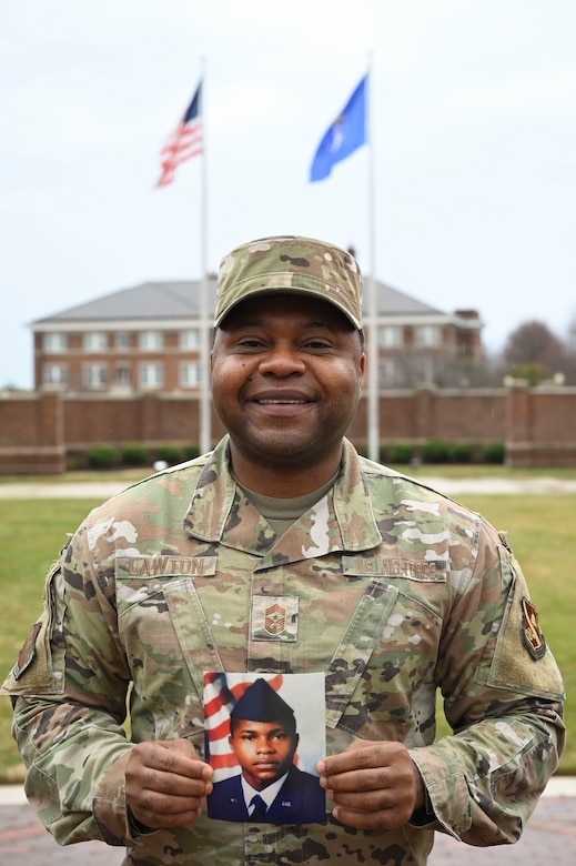 Chief Lawton holds a photo of himself as a young Airman straight out of boot camp while on the ceremonial lawn on Joint Base Anacostia-Bolling.