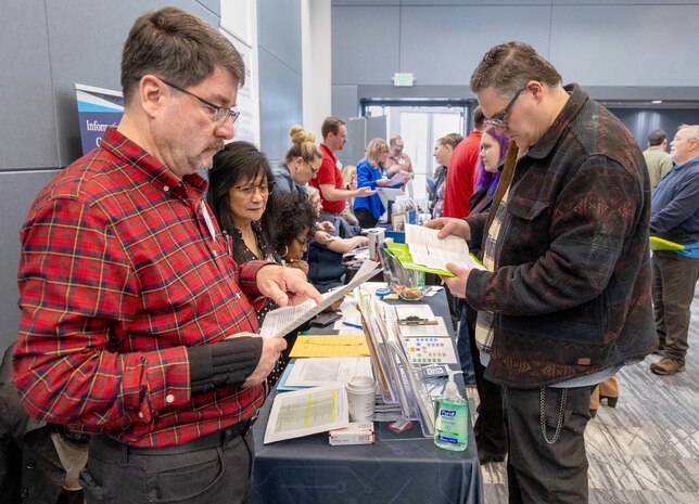 Dave Stefanac, left, IT specialist-systems analyst, Code 109, IT and Cyber Security, looks over an employment résumé, Feb. 23, 2024, during a two-day Puget Sound Naval Shipyard & Intermediate Maintenance Facility Hiring Fair at the Kitsap Conference Center in downtown Bremerton, Washington. (U.S Navy photo by Wendy Hallmark)