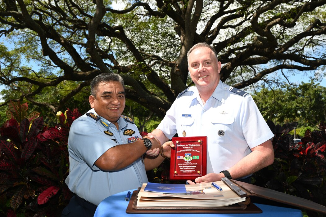 Two generals signing a sister squadron agreement under a tree