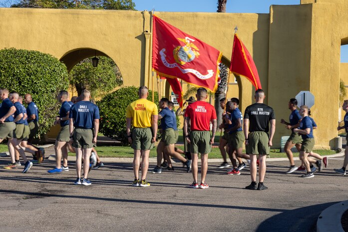 U.S. Marine Corps drill masters with Recruit Training Regiment, stand at attention as the new Marines of India Company, 3rd Recruit Training Battalion, run by at Marine Corps Recruit Depot San Diego, Feb. 22, 2024. The company motivational run is the last physical training event the Marines will conduct before they graduate from MCRD San Diego. (U.S. Marine Corps photo by Cpl. Joshua M. Dreher)